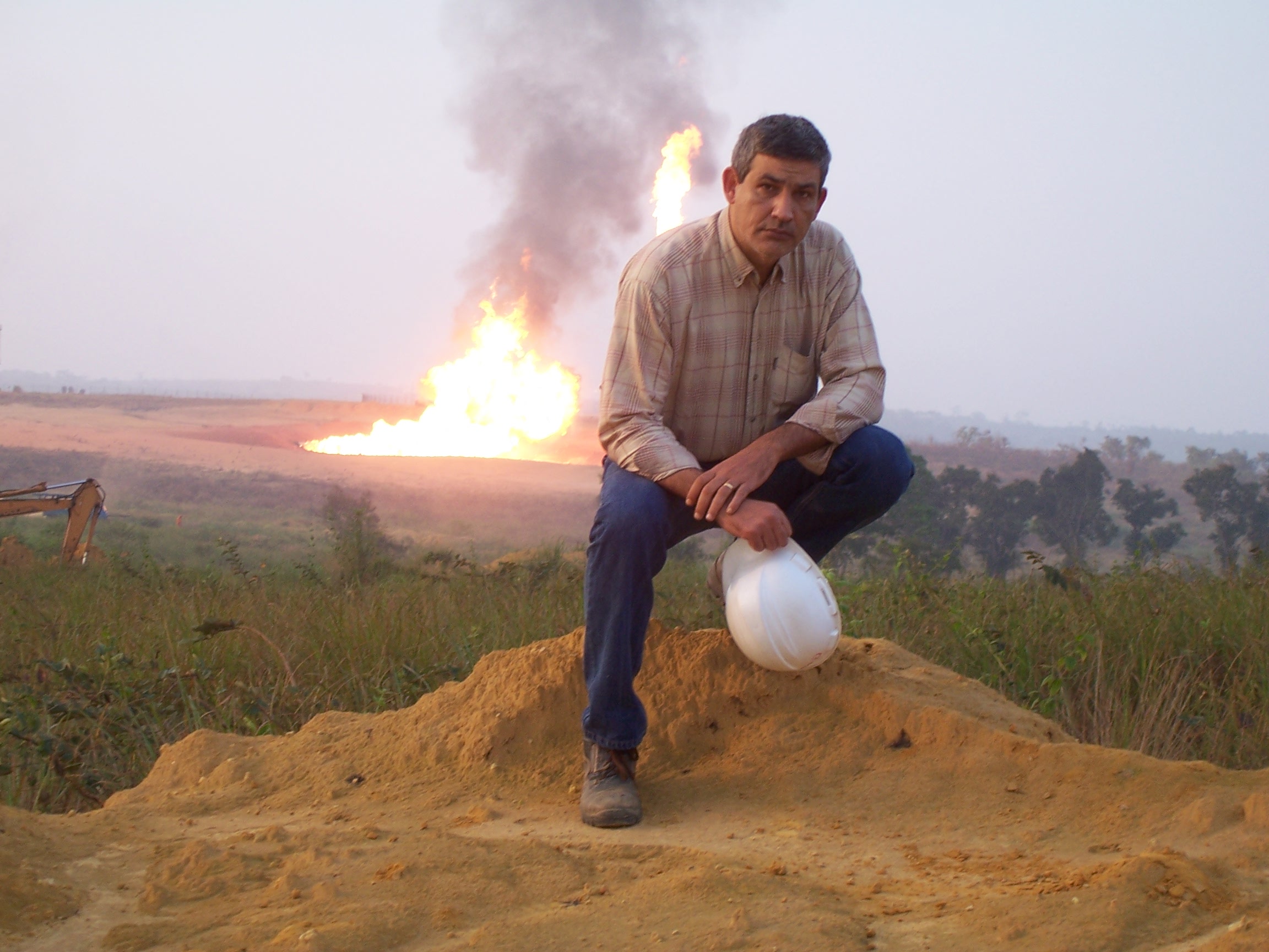 Geologist white helmet gas flaring background